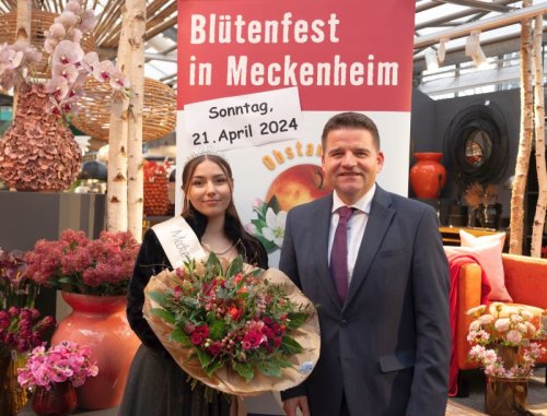 Foto zeigt Blütenkönigin Antonia Augenstein und Bürgermeister Holger Jung vor dem Veranstaltungshinweis zum Blütenfest am 21. April 2024.