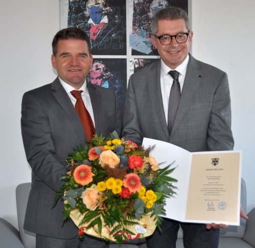 Foto zeigt Bürgermeister Holger Jung und den Ersten Beigeordneten Hans Dieter Wirtz bei der Übergabe der Urkunde.