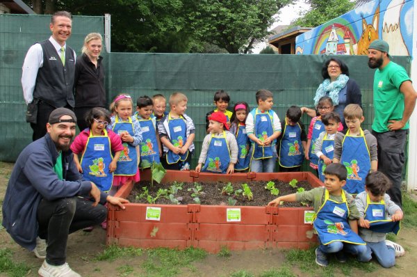 Foto zeigt die Vertreter der Edeka-Stiftung, die heimischen Paten, eine Erzieherin und die Kinder der Kita Villa Regenbogen am Hochbeet.
