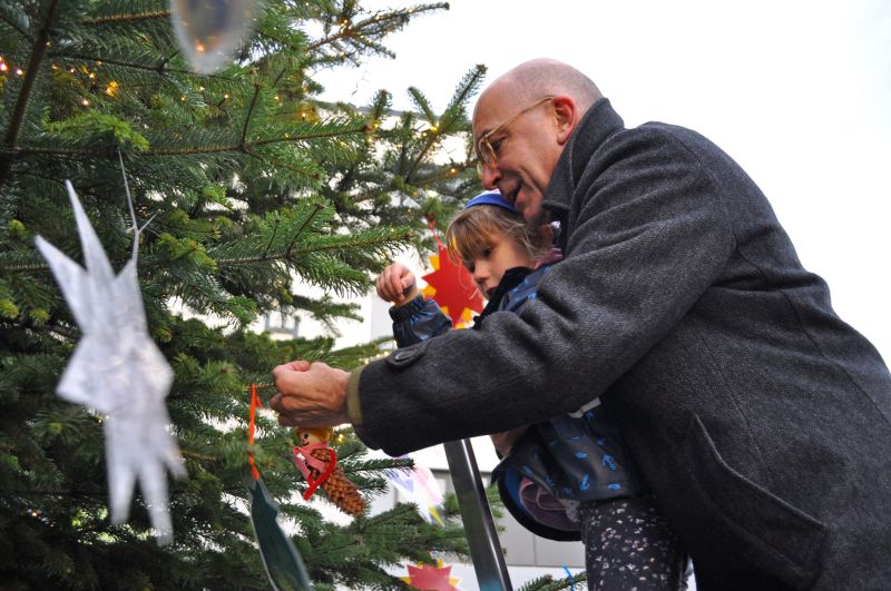 Foto zeigt den Bürgermeister und ein Kita-Kind beim Weihnachtsbaumschmücken.