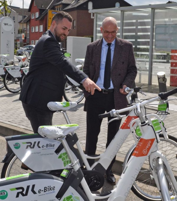 Foto zeigt Bürgermeister Bert Spilles und Christian Seul von der RVK inmitten der E-Bikes.