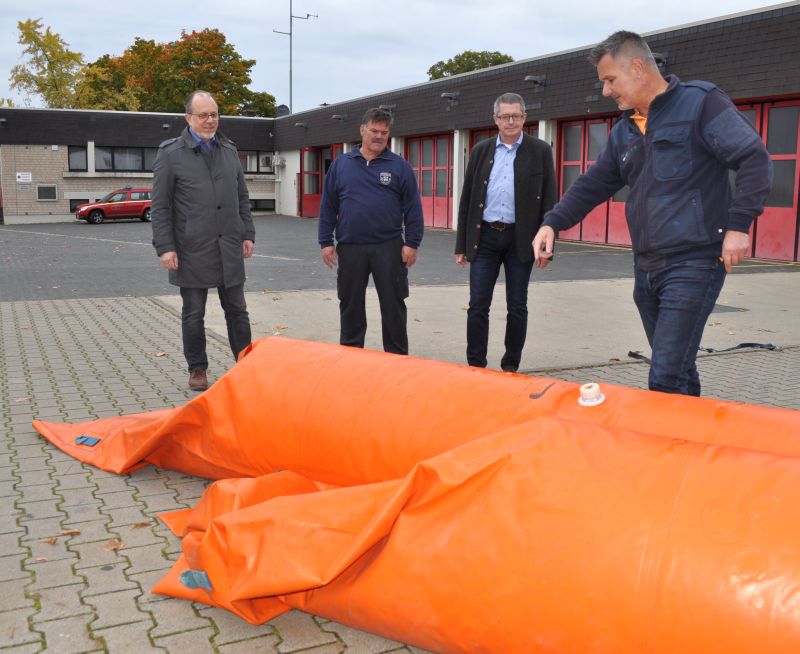 Foto zeigt Heinz-Peter Witt, Günter Wiegershaus, Hans Dieter Wirtz und Andreas Roos mit dem orangefarbenen Schutzsystem vor dem Feuerwehrgerätehaus.